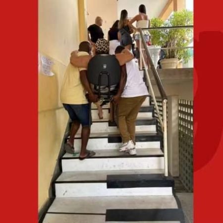 MULHER É CARREGADA EM CADEIRA PARA VOTAR